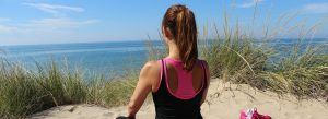 Woman on the beach looking out over the ocean meditating.