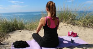 Woman on the beach looking out over the ocean meditating.